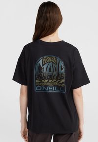 Sort bomulds T-shirt med løs pasform. Har et grafisk print på ryggen med ordene "FROZEN WAVE" i blå og grøn, omkranset af sort.