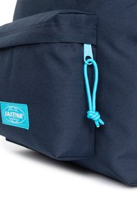 Sac à dos Eastpak bleu marine avec un tissu texturé, doté d'une poche avant et d'un zip bleu vif avec un accent noué.