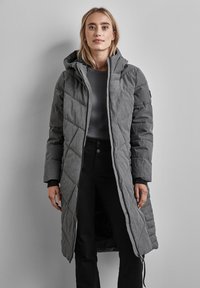 Manteau long gris en duvet avec capuche, présentant un texture en piquage diamant, fermeture éclair à l'avant et accents noirs aux poignets et à l'ourlet.