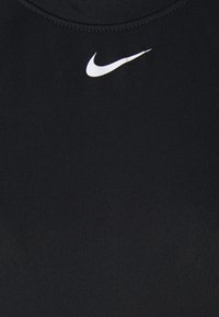 Zwarte atletische tanktop van rekbare stof met een gestructureerd oppervlak en een klein wit Nike-logo op het borstgebied.