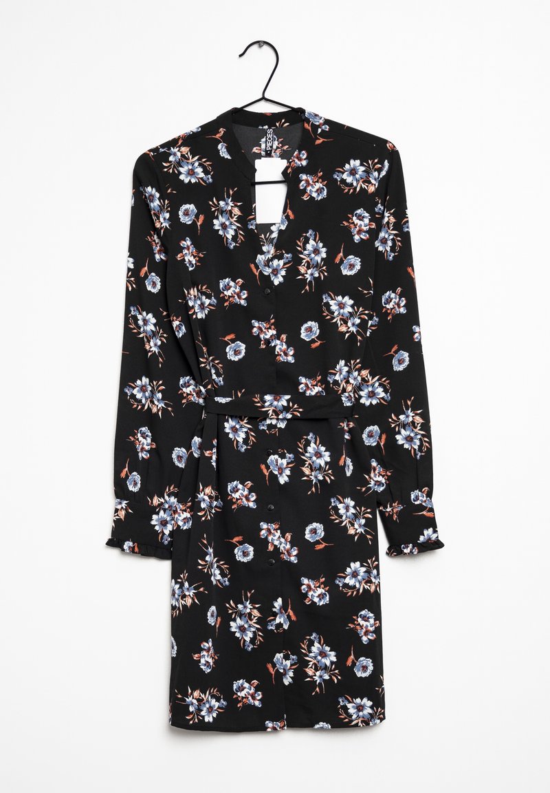Robe noire à manches longues avec imprimé floral bleu et blanc, boutonnée devant, ceinture à la taille et petits volants sur les poignets, suspendue à un cintre noir.