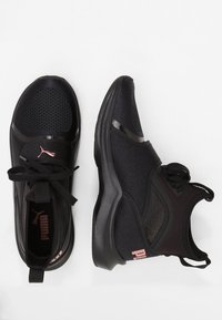 Svarta sportskor med ovandel i mesh, rund tå och framträdande snören. Har en rosa logotyp på sidan och texturerade detaljer på hälen.