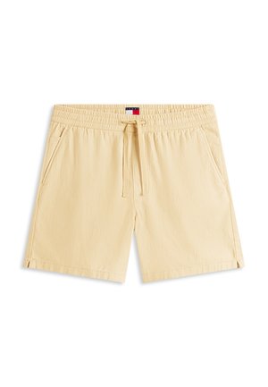 Beiget elastiset vyötäröhousut, joissa on nyöritys, sivutaskut ja pieni punainen, valkoinen ja sininen logotunniste vyötärön keskellä.