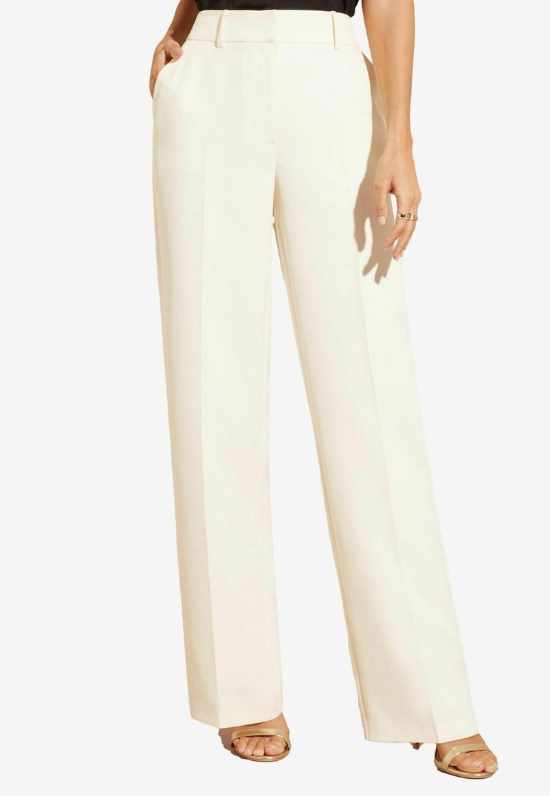 Crème wijdpantalon van gladde stof, hoge taille, precieze plooien en zijzakken, gecombineerd met beige sandaaltjes met straps.