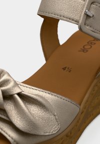 Ασημένιο δερμάτινο σανδάλι πλατφόρμα με λεπτομέρεια φιόγκο, ρυθμιζόμενο λουράκι και υφασμένη σόλα φελλού. Μέγεθος 4,5 τυπωμένο στην εσωτερική σόλα.
