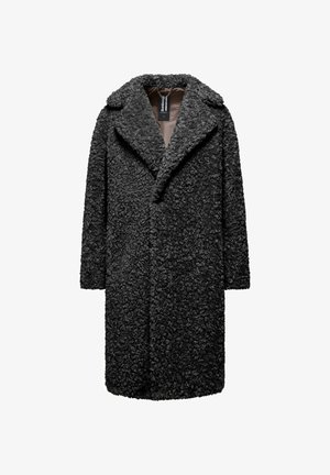 Long black curly faux fur coat with wide lapels and brown inner lining, hanging from a chain on a white background.