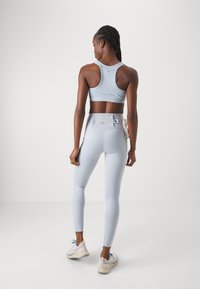 Világoskék sportmelltartó és magas derekú leggings, testhezálló dizájn, puha textúra, hátul és a derékpánton logóval kiemelve.