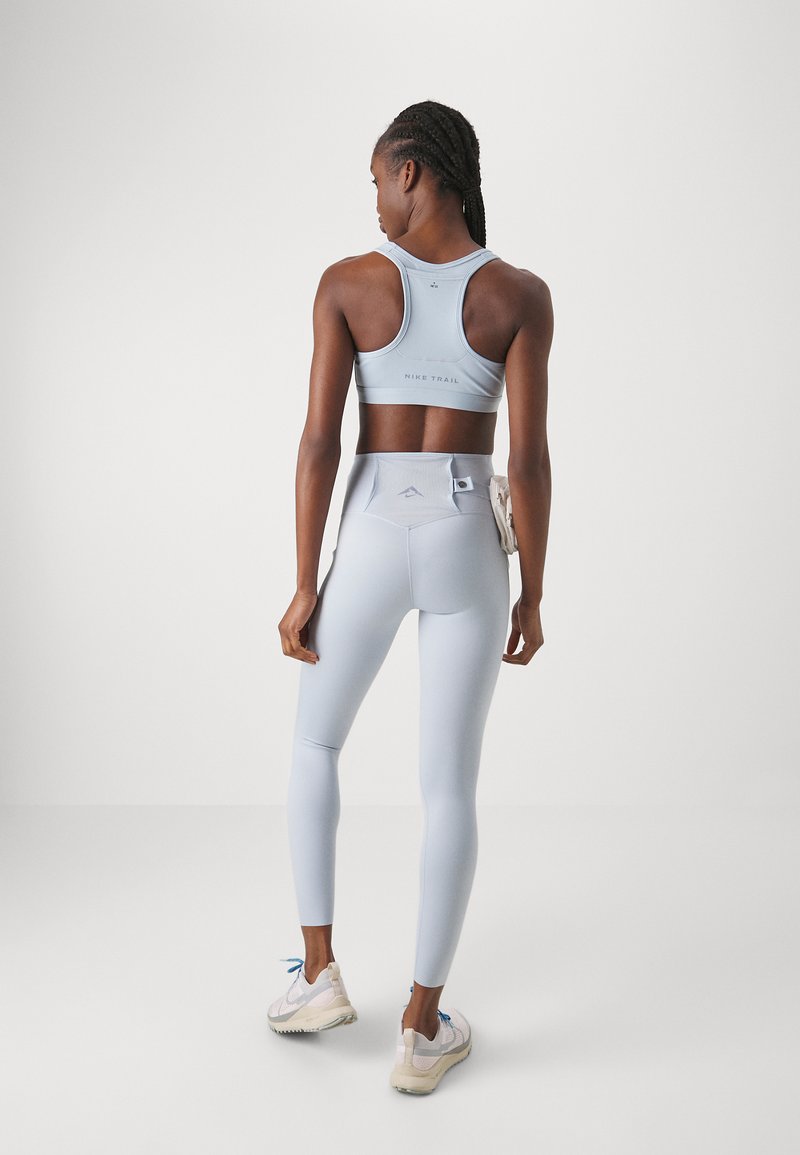 Soutien-gorge de sport bleu clair et leggings taille haute, design ajusté, texture douce, avec des accents de logo dans le dos et à la taille.