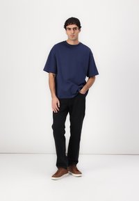 Tricou bleu marin cu mânecă scurtă, asociat cu pantaloni negri și adidași maro. Croială casual, culori uni, textură simplă și design minimalist.