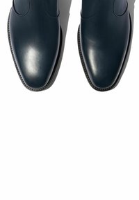 Botas de cuero azul oscuro hasta el tobillo con un acabado suave, puntera afilada y costuras sutiles a lo largo del borde de la suela.