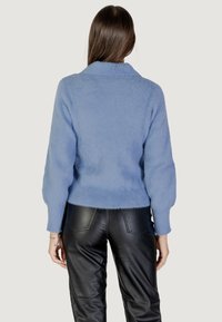 Maglione fluffy azzurro chiaro con colletto, vestibilità rilassata e maniche lunghe, abbinato a pantaloni in pelle nera a vita alta.
