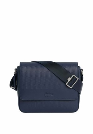 Sac bandoulière texturé bleu marine avec bandoulière noire réglable et logo crocodile embossé sur le rabat avant.