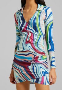 Langärmeliges Kleid mit V-Ausschnitt, das ein mehrfarbiges abstraktes Wirbelmuster in Blau, Pink, Grün und Weiß aufweist, mit einer figurbetonten Silhouette.