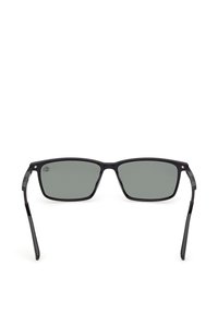 Gafas de sol rectangulares negras con lentes tintadas oscuras y varillas delgadas, mostradas sobre un fondo blanco.