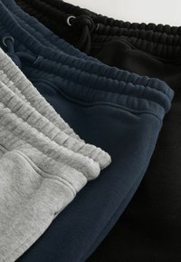 Trīs sporta bikses pelēkā, tumši zilā un melnā krāsā, ar elastīgu jostu un auklītēm, kā arī ribotām aprocēm. Kokvilnas maisījuma materiāls.