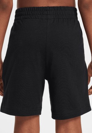 Zwarte korte broek met elastische tailleband, gedragen door een persoon die van achteren zichtbaar is, met zicht op de bovenbenen en het onderste deel van de torso.