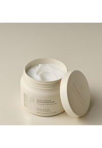 Vit rund burk med ett ljust beigefärgat lock, märkt "BOND REPAIR NOURISHING MASK." Innehåller en slät vit kräm inuti, med en kapacitet på 200 ml.