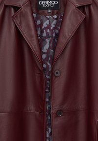 Giacca in pelle bordeaux con colletto revers, due bottoni e fodera interna decorata con cinture e fibbie.