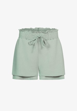 Gaiši zaļas šorti, kas izgatavoti no mīkstas auduma, ar gāztu jostu ar viļņotu malu un auklu. Apakša satur sānu šķēlumu.