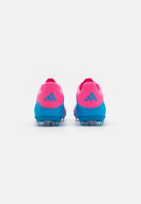 Adidas nogometni štikli z roza mrežastim zgornjim delom in modrimi akcenti. Imajo prozorne stubice za oprijem in ergonomsko zasnovo za boljšo učinkovitost.