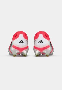 Τα ποδοσφαιρικά παπούτσια Adidas διαθέτουν έναν λευκό και ροζ σχεδιασμό, με απαλό υφή, στρογγυλό σχήμα και μαύρες ρίγες στα πλάγια.