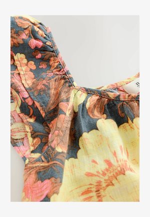 Top con estampado floral y tejido ligero. Presenta detalles de costura fruncida, un fondo gris oscuro azul y acentos de amarillo, naranja y rosa.