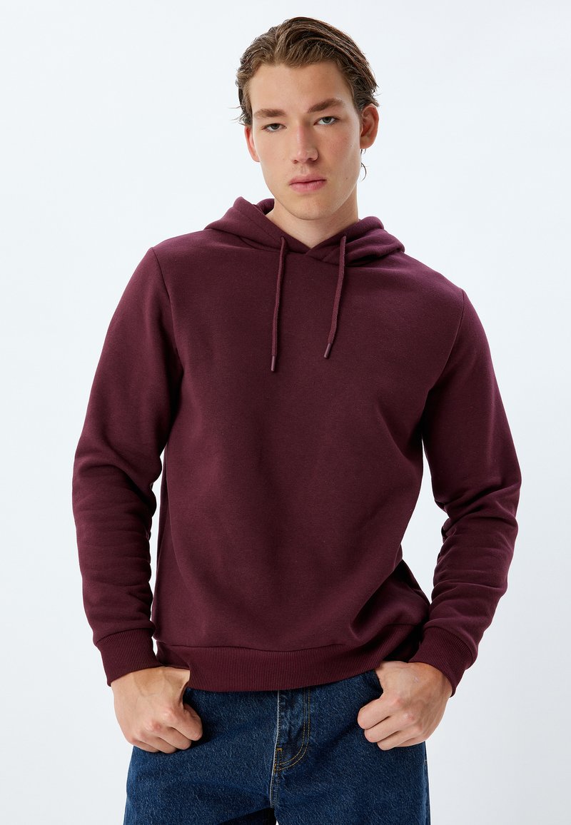 Hoodie bordeaux con tasca a marsupio, cappuccio con cordino e polsini a coste. Realizzato in tessuto morbido, presenta una vestibilità rilassata e un design minimale.
