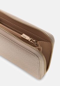 Portafoglio beige con texture, cerniera dorata, dotato di più scomparti e tiretto della cerniera con logo. Fodera interna liscia.