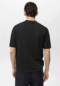 Black short-sleeve knit shirt with a subtle textured pattern, a collar, and rolled cuffs, featuring a relaxed fit and solid color.