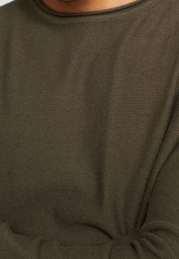 Maglione a maglia verde oliva con tessuto texturizzato, scollatura rotonda e maniche lunghe. La vestibilità sembra rilassata e leggera.