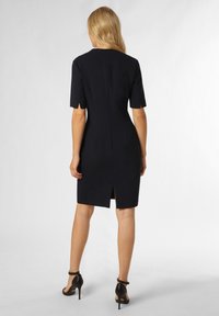 Dunkelblaues, figurbetontes Kleid mit kurzen Ärmeln, einem Reißverschluss auf der Rückseite und einem dezenten Schlitz am Saum, das einen glatten Stoff und ein maßgeschneidertes Design präsentiert.