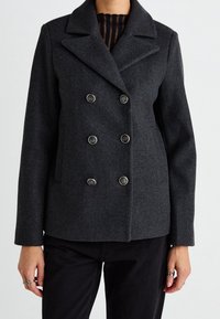 Blazer de lana gris de doble botonadura con grandes botones, solapa muesca y bolsillos laterales. Presenta un ajuste entallado y una textura suave.
