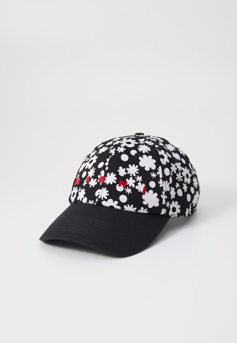 Gorra de béisbol negra con un patrón floral blanco, texto rojo bordado en la parte frontal y visera negra lisa. La textura del tejido es suave.