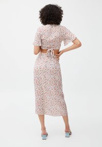 Robe midi à imprimé floral avec manches courtes, détail de nœud dans le dos et silhouette ajustée. Présente des fleurs multicolores sur un fond clair.