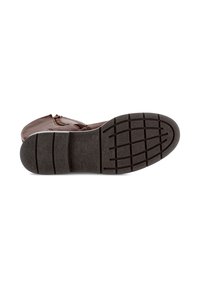 Bota de tobillo marrón apoyada de lado que muestra suela de goma negra con patrones de relieve y un zipper lateral.