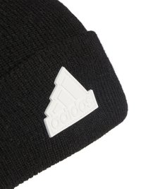 Bonnet en tricot noir avec une surface texturée et un patch en caoutchouc blanc avec le logo Adidas en forme de triangle sur le devant.
