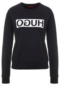 Felpa nera a maniche lunghe con polsini e orlo a costine, caratterizzata da un logo rettangolare bianco con il testo invertito in nero "HUGO" sul petto.