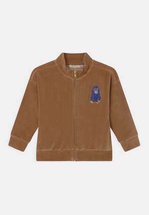 Veste zippée en velours côtelé marron avec une texture striée, ornée d'une broderie d'animal bleue sur le côté gauche et d'un col montant.