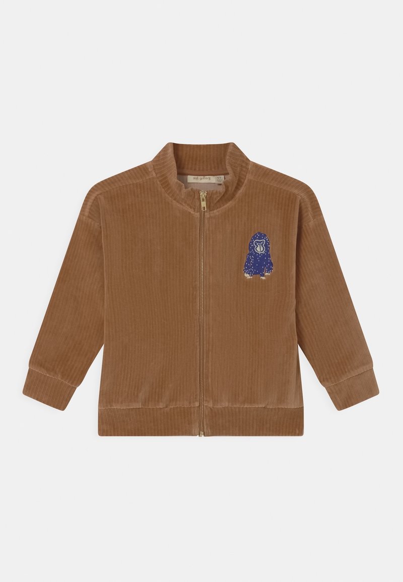 Veste zippée en velours côtelé marron avec une texture striée, ornée d'une broderie d'animal bleue sur le côté gauche et d'un col montant.