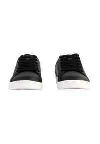 Zapatillas de piel negra con suelas de goma blanca, con cordones negros y un diseño minimalista. Textura suave con detalles de costura sutil.