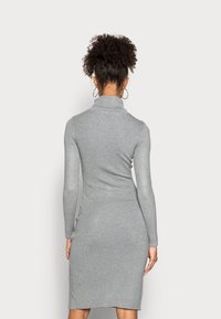 Robe grise à manches longues ribbées avec un col montant, au design ajusté et longueur genou. Présente une texture lisse et des fentes sur les côtés.
