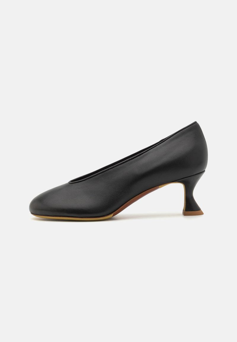 Sapato de salto alto em couro preto com bico fino e um design de salto angular único. Textura suave e estilo minimalista.