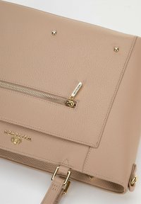 Borsa a tracolla in pelle beige con superficie texture, tasca con zip, dettagli in hardware dorato e logo sul davanti.