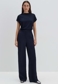 Top blu navy a maniche corte abbinato a pantaloni a gamba larga a vita alta. Entrambi realizzati in tessuto liscio, creando un look coeso e minimalista.