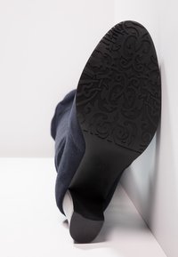 Bota de tobillo de tela azul marino con suela de goma negra texturizada que presenta un patrón ornamentado y un tacón moderado y ligeramente estrecho. Talla 37.