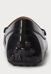 Čierne lakované kožené topánky s hladkým povrchom, s guľatou zadnou časťou a gumovými protišmykovými bodkami na podrážke pre lepšiu priľnavosť.