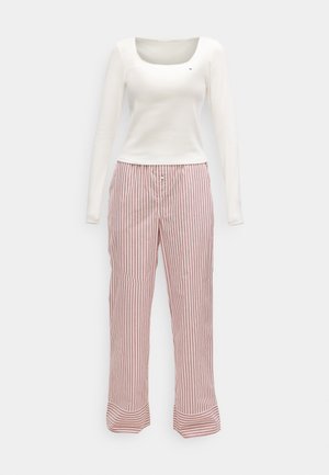 Haut blanc à manches longues avec décolleté rond, assorti à un pantalon de pyjama taille haute à jambes droites avec des rayures verticales rouges et blanches.