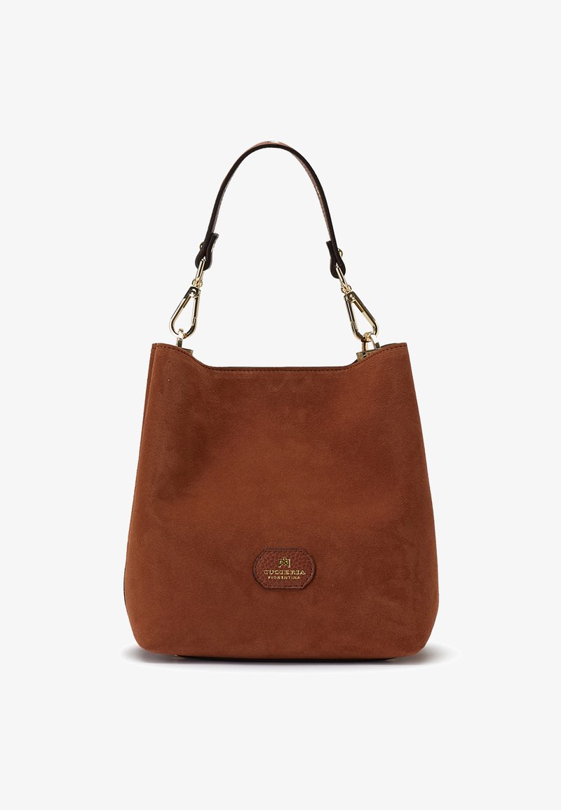 Sac à main en daim marron avec une lanière marron foncé unique attachée par des fermoirs dorés et un petit patch de logo à l’avant.