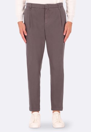 Pantaloni grigi a pieghe con una trama liscia, vestibilità affusolata, tasche laterali e passanti per cintura, abbinati a sneakers bianche.