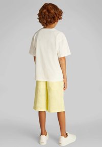 Wit katoenen t-shirt gecombineerd met lichtgele shorts. Gekenmerkt door een ontspannen pasvorm en zachte textuur, aangevuld met witte sneakers.